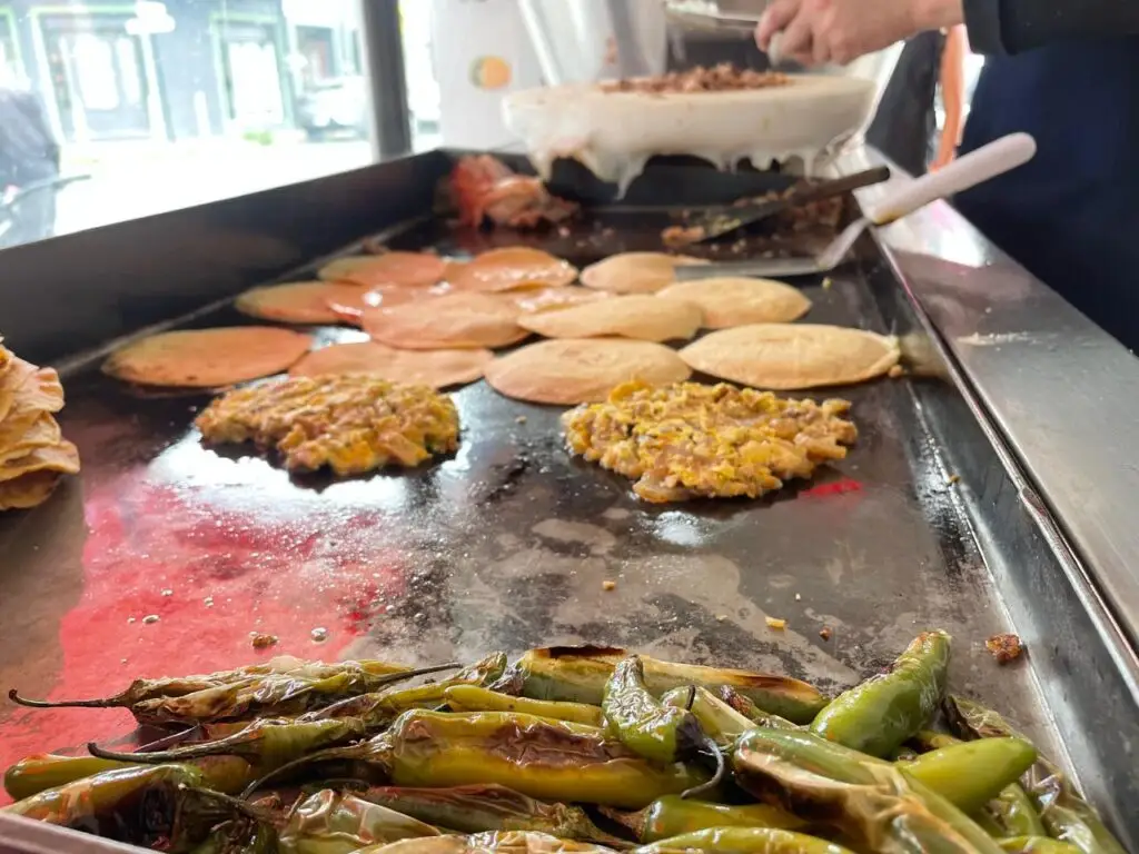 Plancha con tortillas, revolcados y chiles toreados en un servicio de carnitas Santo Cazo